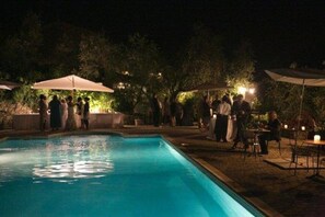 Guests can enjoy a refreshing swim in the pool surrounded by a low wall and paved walkway.