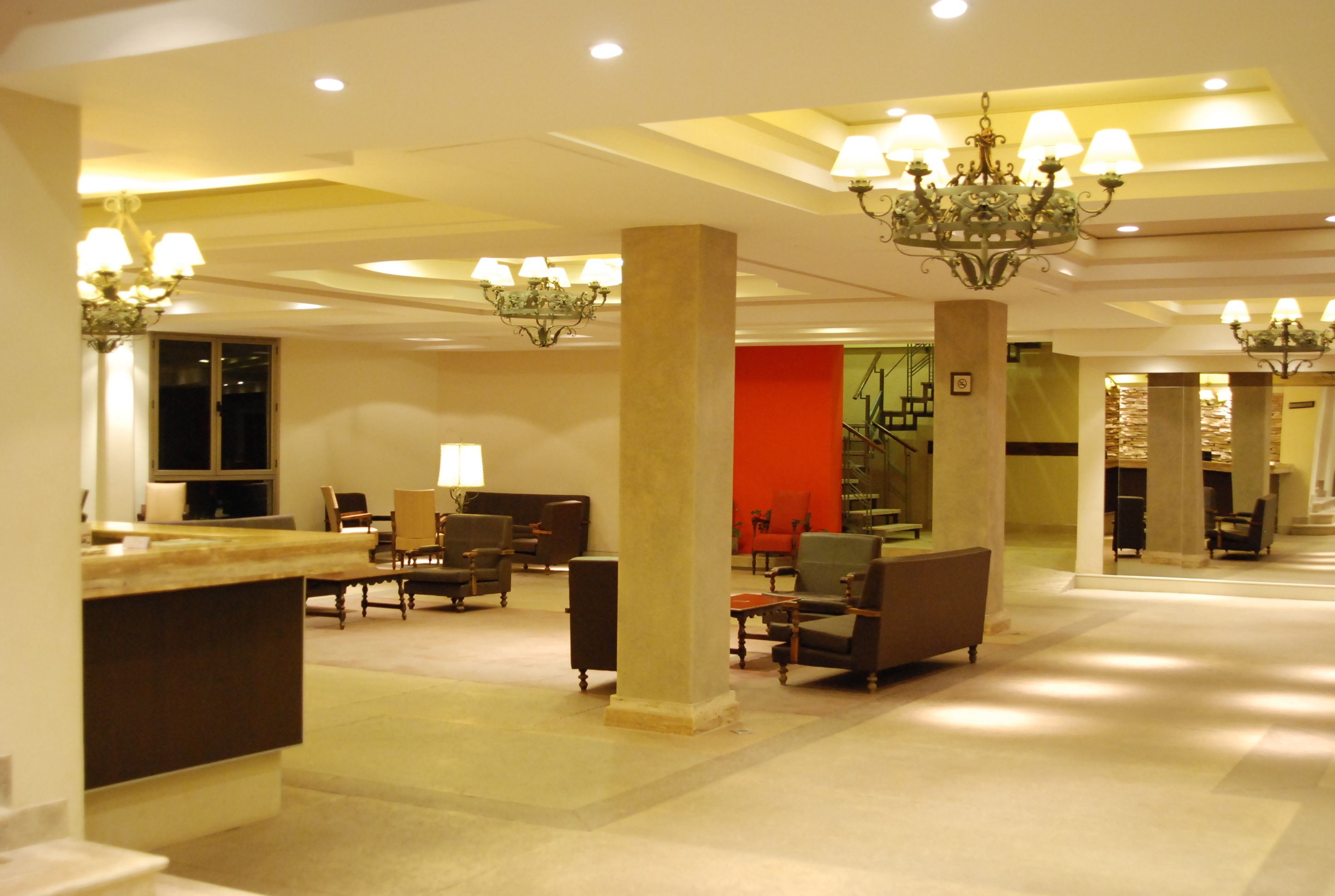 A spacious lobby with multiple seating areas, a reception desk, and a staircase leading to an upper level.