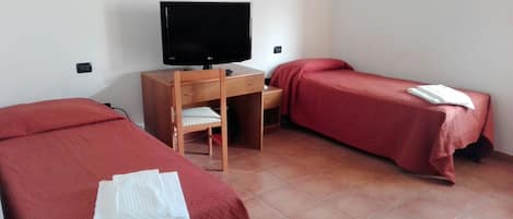 A room with two beds, a desk with a television, and a chair.