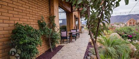 Edificio de ladrillo con un patio que tiene suelo de piedra y mobiliario exterior.