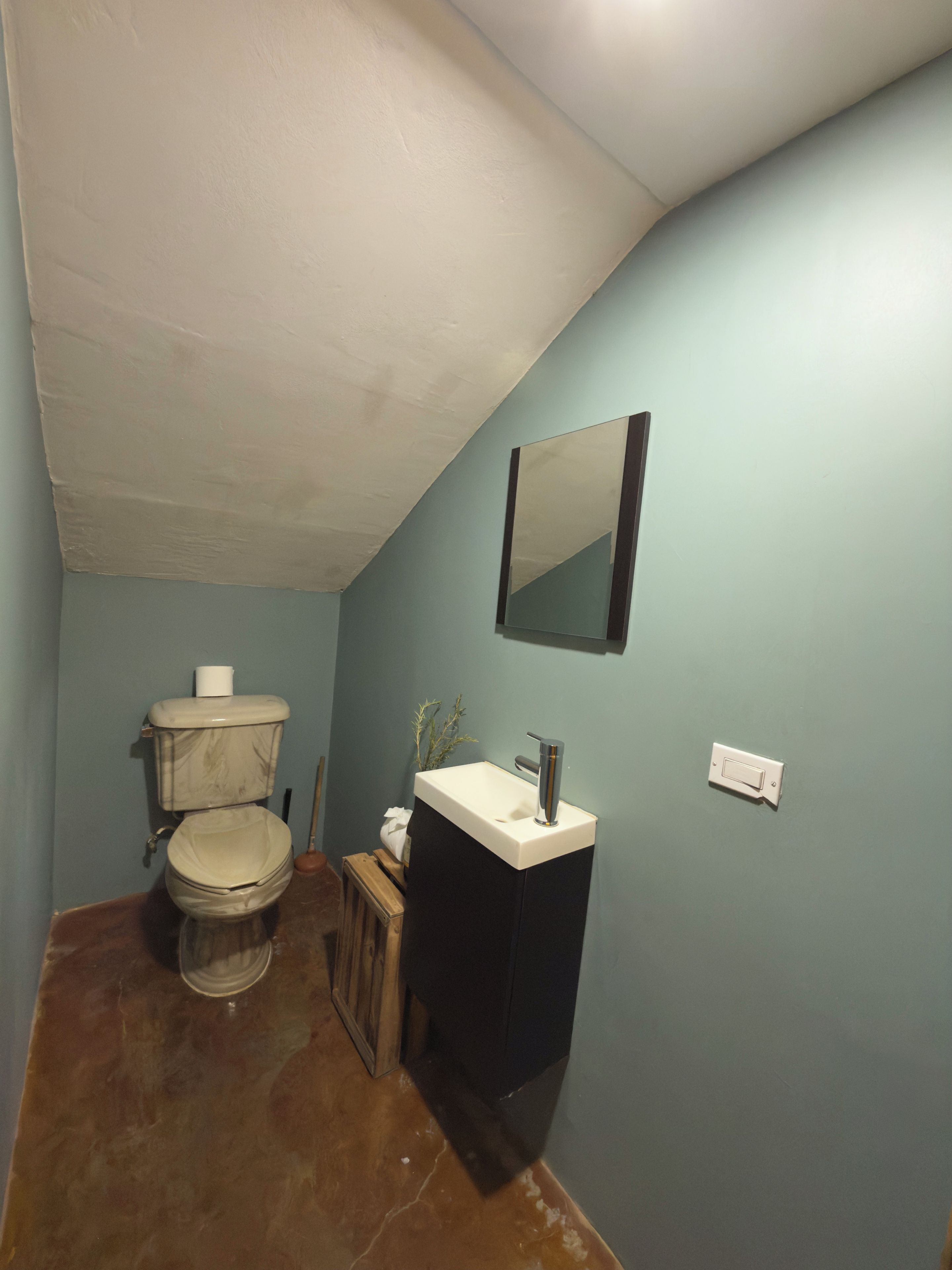 Un baño pequeño con inodoro, lavamanos y espejo.