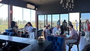 An indoor dining area with large windows, a bar area, and hanging light fixtures. - Don Tomas Viñedo Cabañas (Valle de Guadalupe)