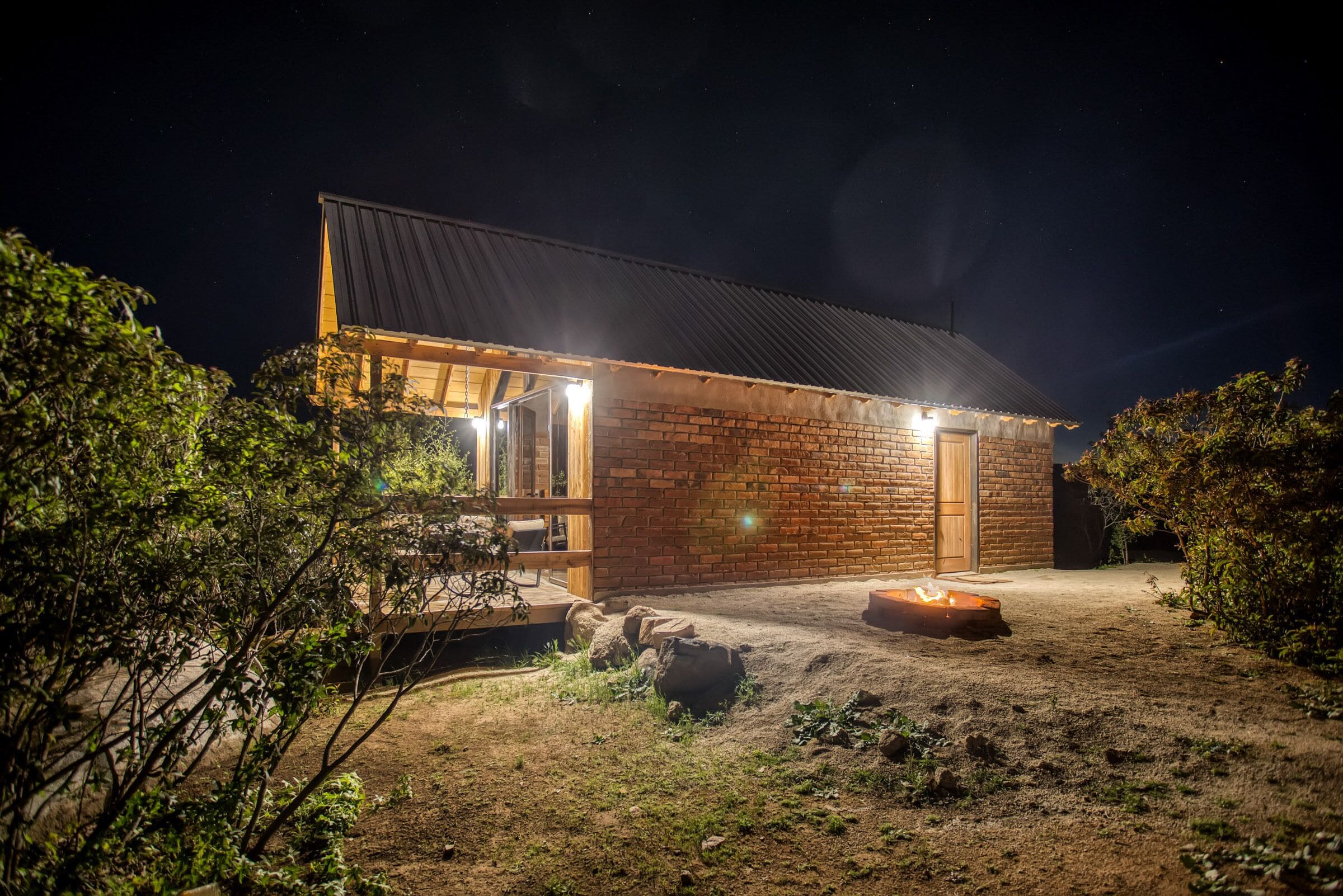 A modern house with a brick exterior, a wooden deck, and a fire pit in the yard.
