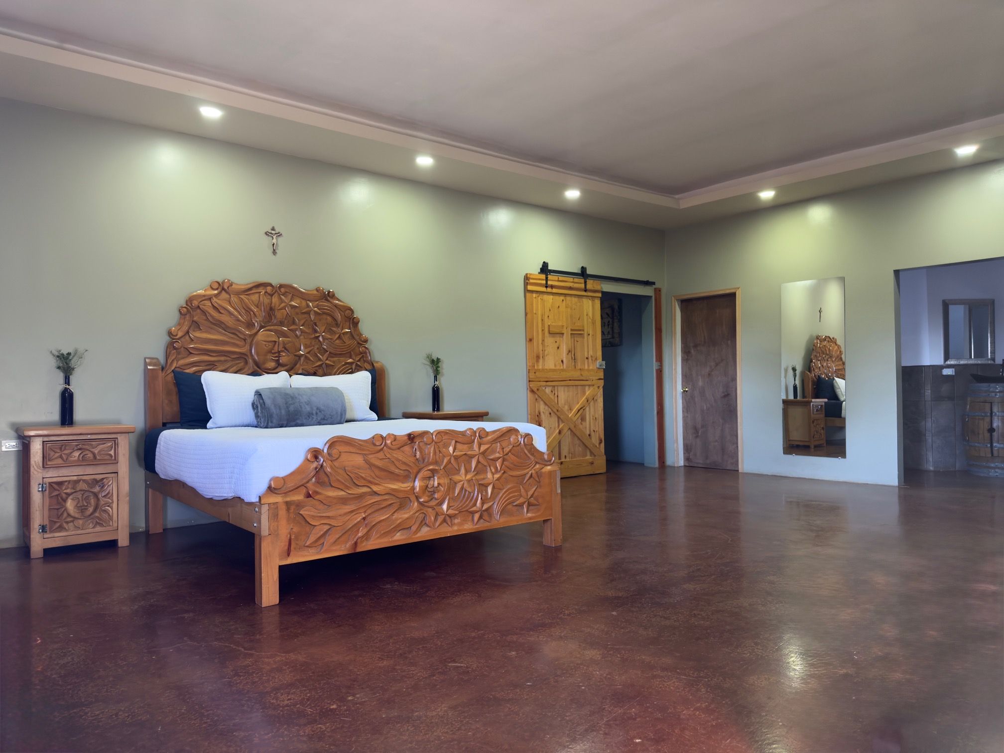 Une chambre spacieuse avec un grand lit, une armoire en bois et un petit meuble.