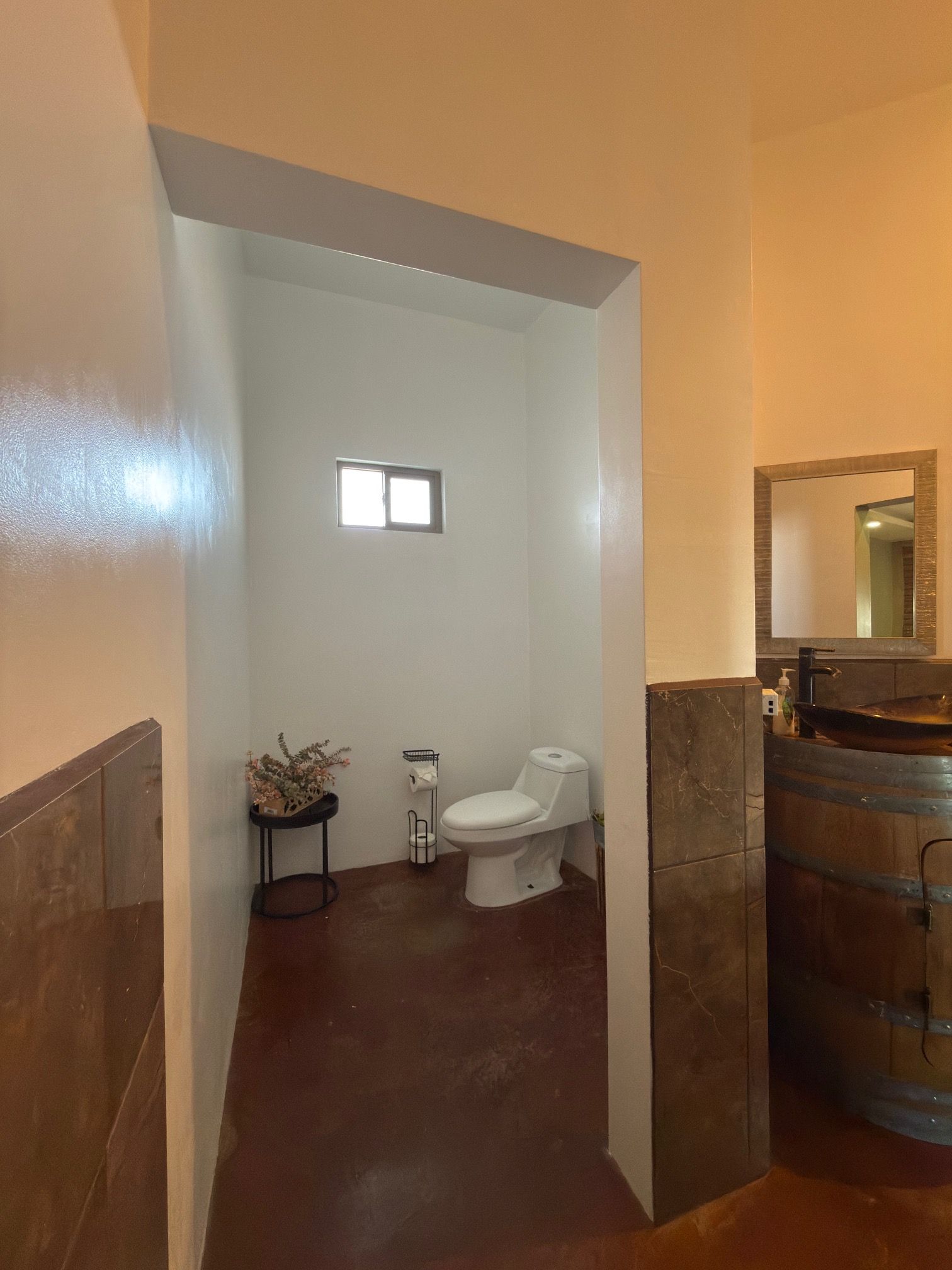 A bathroom with a toilet, a small sink, and a mirror.