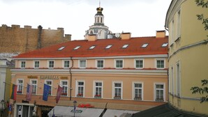 A hotel with a red tiled roof, multiple windows, and a prominent tower with a golden spire. - 2 Bedroom Apartment near Town Hall (Vilnius)