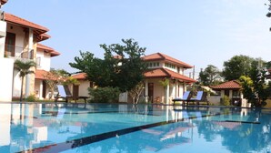 Ein Swimmingpool mit klarem, blauem Wasser, umgeben von Liegestühlen und Palmen.
