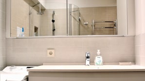 A bathroom with a toilet, sink, and mirror. - Brand New Labdariu Str Apartment (Vilnius)