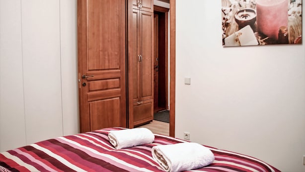 A bedroom with a bed, a wooden wardrobe, and a wall-mounted artwork. - Brand New Labdariu Str Apartment (Vilnius)