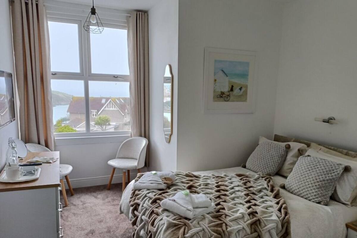 A bedroom with a bed, a chair, a desk, and a window with curtains.