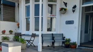 A hotel entrance with a bench, a chair, and potted plants.