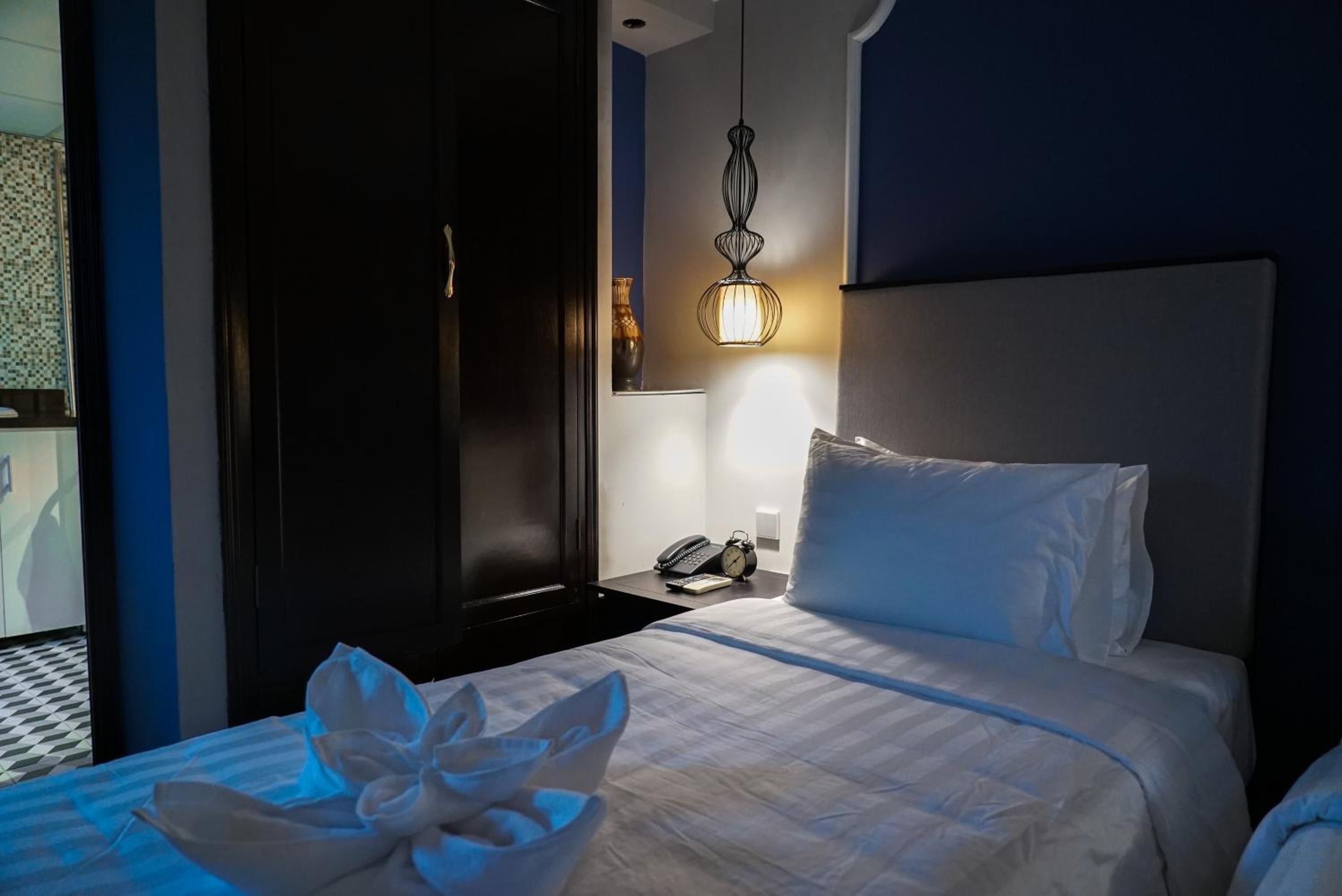 Une chambre d’hôtel avec un lit, une table de chevet et une lampe fixée au mur.