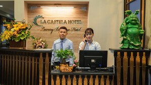 Un mostrador de recepción en el Hotel La Casteia con un fondo de madera, una recepcionista y un monitor de computadora.