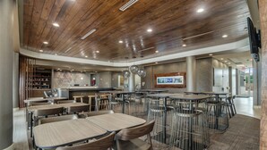 Ein modernes Restaurant mit Holzbalkendecke, mehreren Tischen und Stühlen sowie einer Theke.