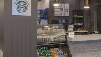 Una cafetería Starbucks con un menú, una vitrina con pasteles y un refrigerador para bebidas.