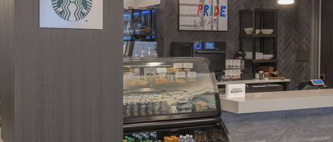 A Starbucks coffee shop with a menu board, a display case with pastries, and a beverage cooler.