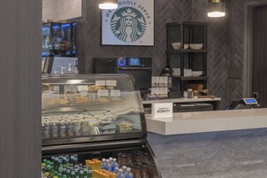 Una cafetería Starbucks con una estación de autoservicio para bebidas, un menú digital y un letrero que indica una ubicación Marriott Bonvoy.
