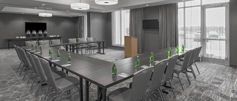 A conference room with a long table, chairs, and a podium.