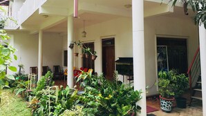 A covered outdoor area with a balcony, potted plants, and a grill.
