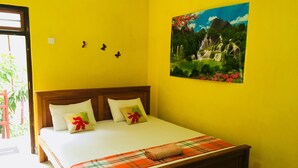 A bedroom with a bed, pillows, a blanket, a painting, and a door.