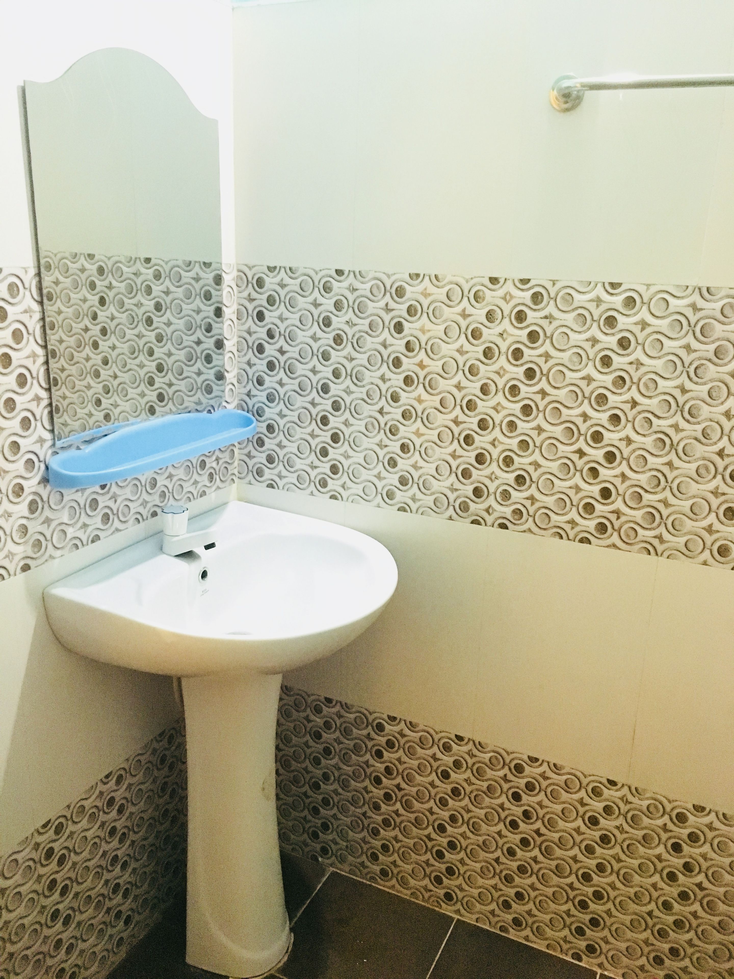 A bathroom with a white sink, a blue soap dish, patterned tiles, and a mirror.
