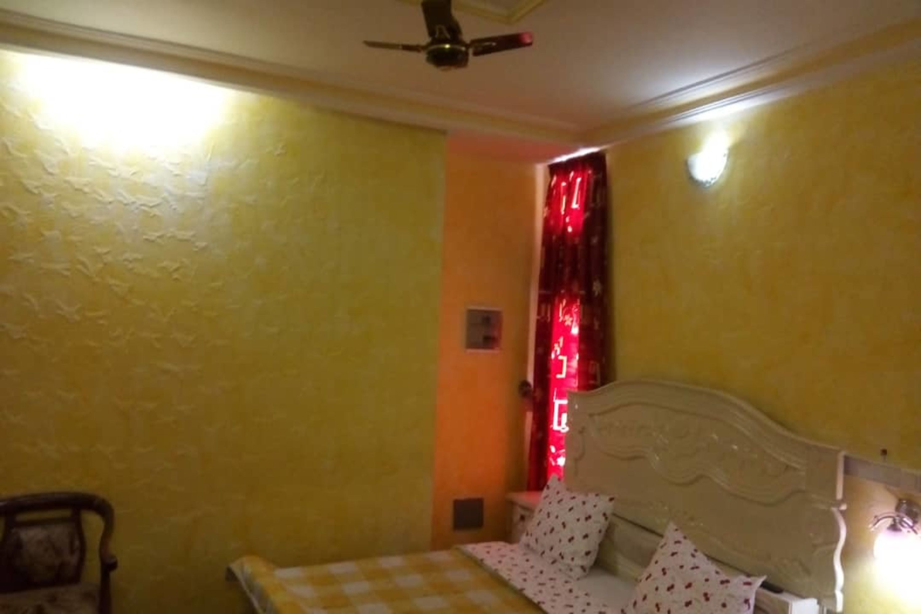 A bedroom with a bed, a chair, and a ceiling fan.