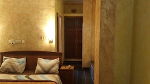 A hotel room with a bed, bedside table, and a door leading to a bathroom.