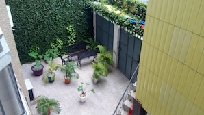 A rooftop garden with a seating area, potted plants, and a green wall.