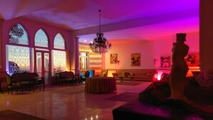 Un hall d’entrée spacieux, doté de fenêtres en arc de cercle, d’un lustre et d’une table ronde.