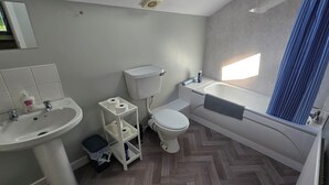 A compact bathroom with a white sink, toilet, and bathtub. - Castleton Gardens Apartments Belfast (Belfast)