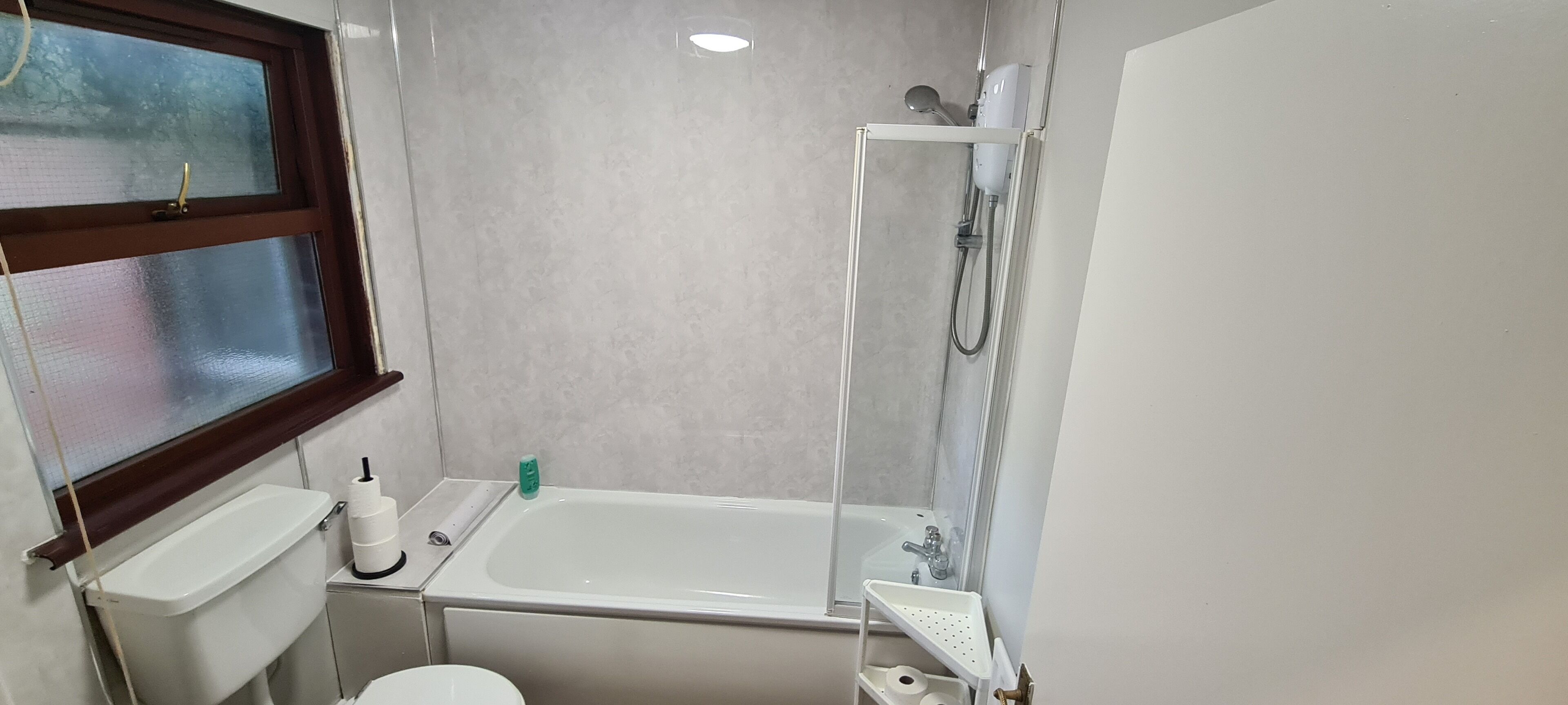 A bathroom with a toilet, a bathtub, a shower, and a window.