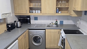 A compact kitchen with a washing machine, a microwave, a toaster, and a sink. - Castleton Gardens Apartments Belfast (Belfast)
