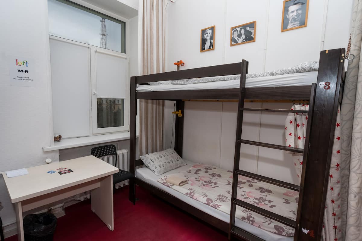 A bunk bed with floral bedding, a desk with a chair, and a radiator.