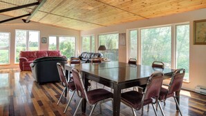 Une pièce spacieuse avec une grande table en bois et des chaises, un canapé rouge et un divan en cuir noir.