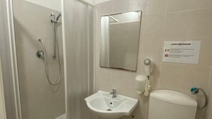 A bathroom with a glass-enclosed shower, a sink, a toilet, and a mirror.