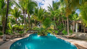 A pool surrounded by palm trees and lounge chairs.