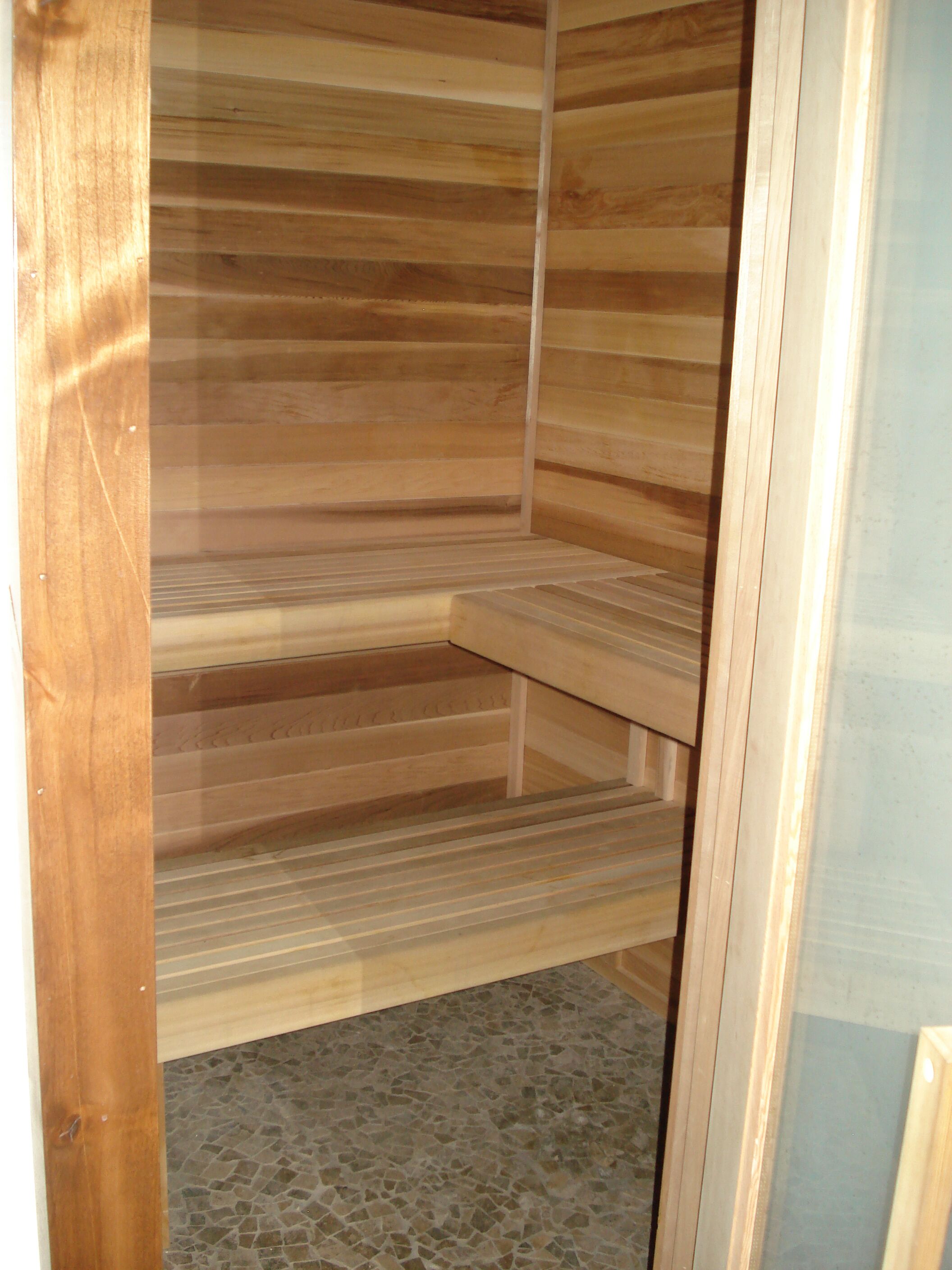 Una sauna con bancos de madera y piso de mosaico.