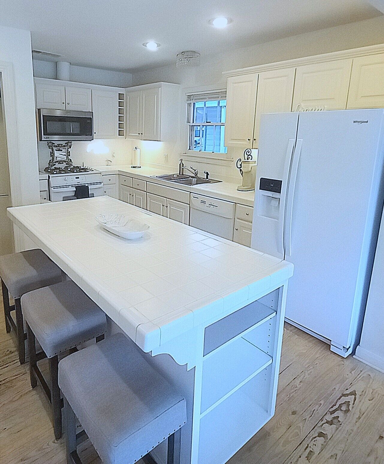 A kitchen with a central island, a refrigerator, and a microwave.