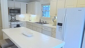 A kitchen with a central island, a refrigerator, and a microwave. - Uptown Downtown Office, Fenced Yard, Pools, Walk to Parks, Near Major Employers (Austin)