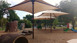 A playground with shaded areas, wooden structures, and a slide. - Uptown Downtown Office, Fenced Yard, Pools, Walk to Parks, Near Major Employers (Austin)