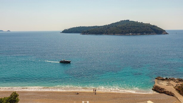 A beach with a boat, a small island, and a clear sky. - Hedera Estate, Hedera A19 (Dubrovnik)