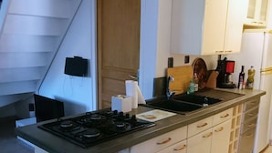 Una cocina con una isla central, armarios blancos, una estufa y un fregadero.