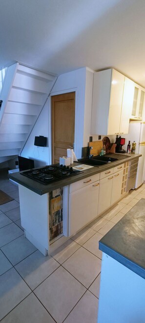 A kitchen with a central island, white cabinets, a stove, and a sink. - House, garden in Vieux Boucau (Vieux-Boucau-Les-Bains)