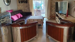 Ein gemütliches Wohnzimmer mit einer Steinsäule, einem Sofa mit rosafarbenen Kissen, einem Holztisch und einem Fernseher.