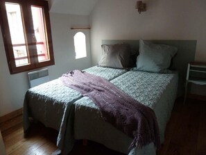 Ein Schlafzimmer mit einem Bett, einem Fenster, einer Wandleuchte und einer Heizung.