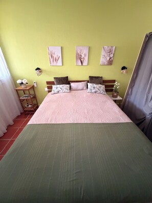 A bed with a green bedspread, a wooden headboard, and two nightstands with lamps.