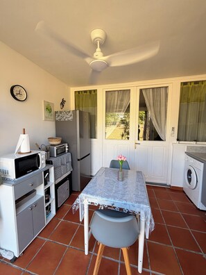 A compact kitchen with a dining table, a microwave, a refrigerator, and a washing machine.