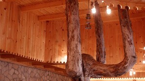 Ein Holzinterieur mit einem großen Baumstamm als Mittelpunkt, einer Steinwand und Holzverkleidung.