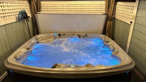Ett bubbelbad med en digital display, omgivet av träpanel och en vit avskärmning för att skapa avskildhet.