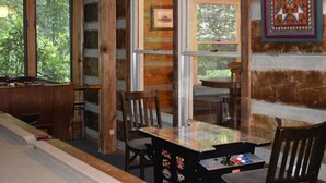 Ein gemütliches Blockhaus-Interieur mit Billardtisch, Holzstühlen und Esstisch.